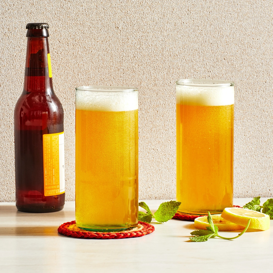 Summer Shandy cocktail with bottle of beer, and 2 glasses filled with cocktail and lemon wheels