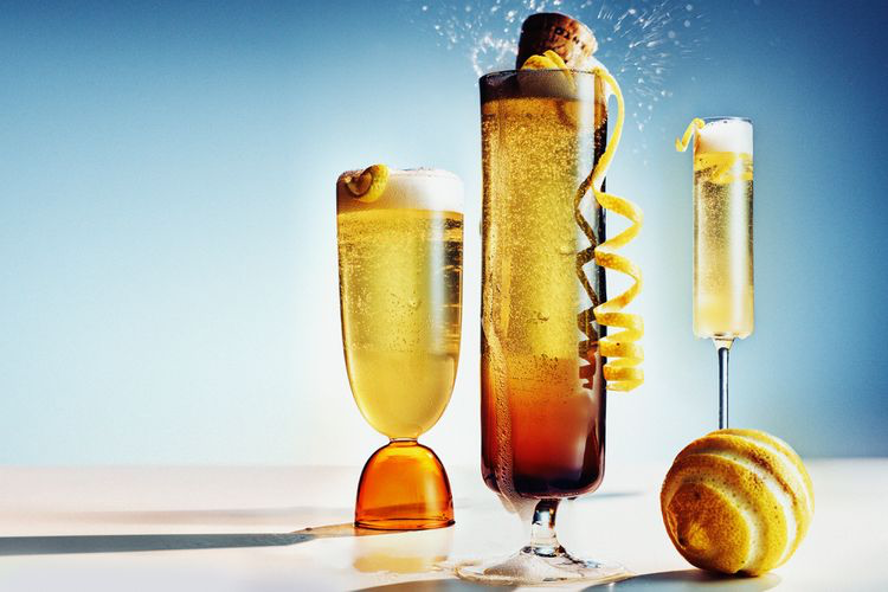 French 75 cocktail with lemon curls, champagne flutes, a cork, and lemon spiral