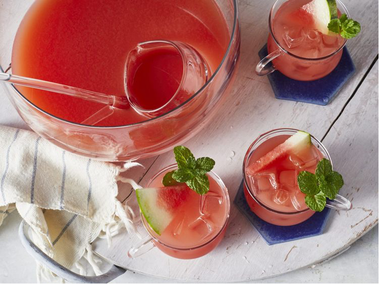 Watermelon punch in bowl with iced cups garnished with mint, watermelon.