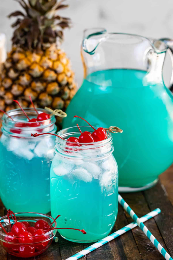 Pitcher of Blue Hawaiian punch served in mason jars with red cherries