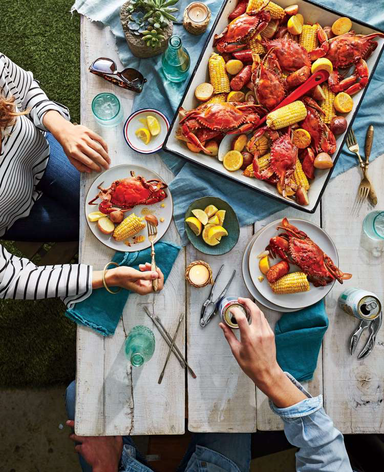 Chesapeake Bay Crab Boil served on picnic table in a tray with overview of guests eating on plated food