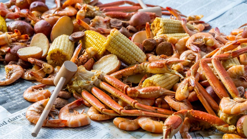 Low Country Seafood Boil (Frogmore Stew) served on newspaper with wooden mallet 