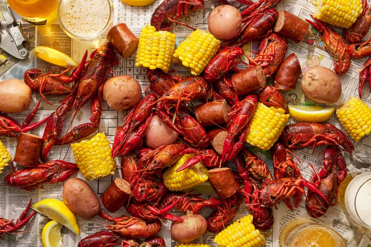 Cajun Crawfish Boil served on newspaper with glasses of beer