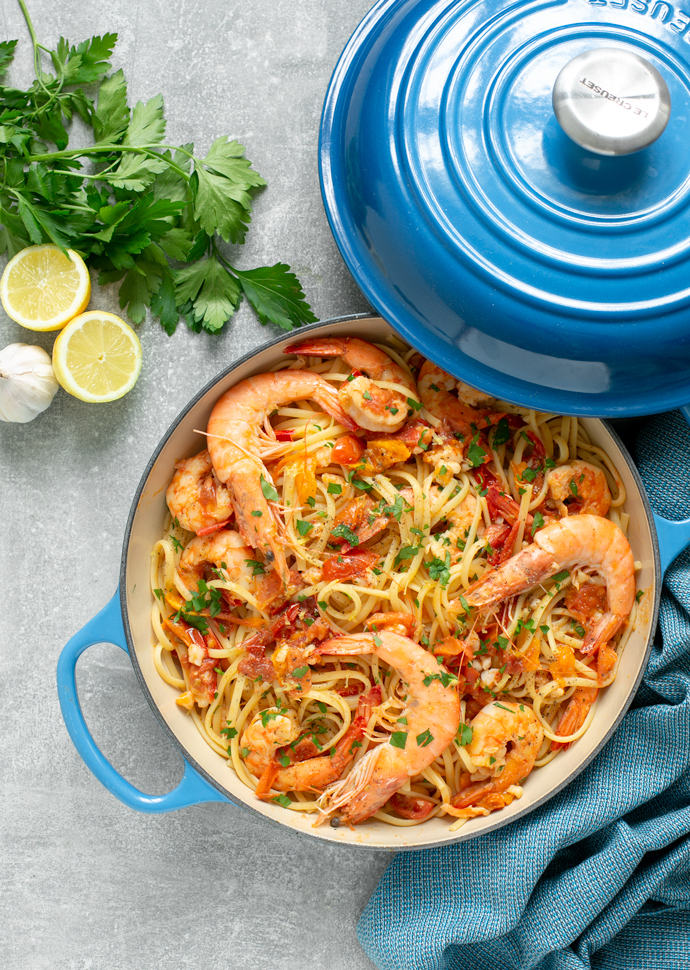 Authentic Italian  Prawn Linguine in a blue pot with fresh parsley, lemon haves, and clove of garlic