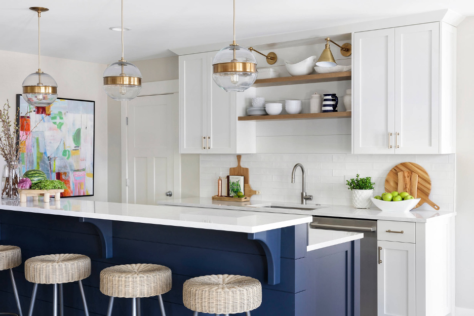 small beach house kitchen with extended bar above countertop and barstools, white cabinetry, pendant lights, navy blue cabinet base, bright accents