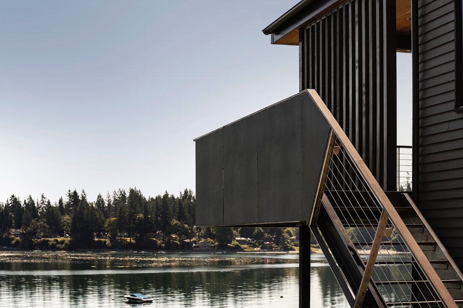 Outdoor stairwell and slatted screen transitioning wall in outdoor area of Home House in Puget Sound. Water views and boat in the water.