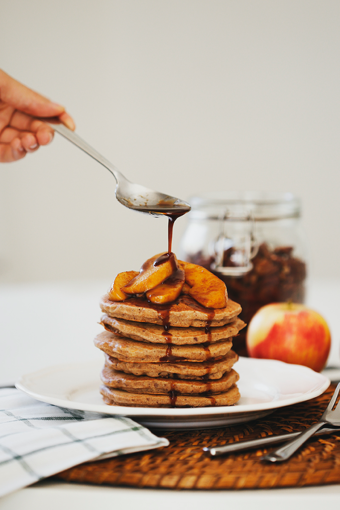 Apple Buckwheat Pancakes with Coconut Caramel Apples on a plate with Gala apple and mason jar in background.