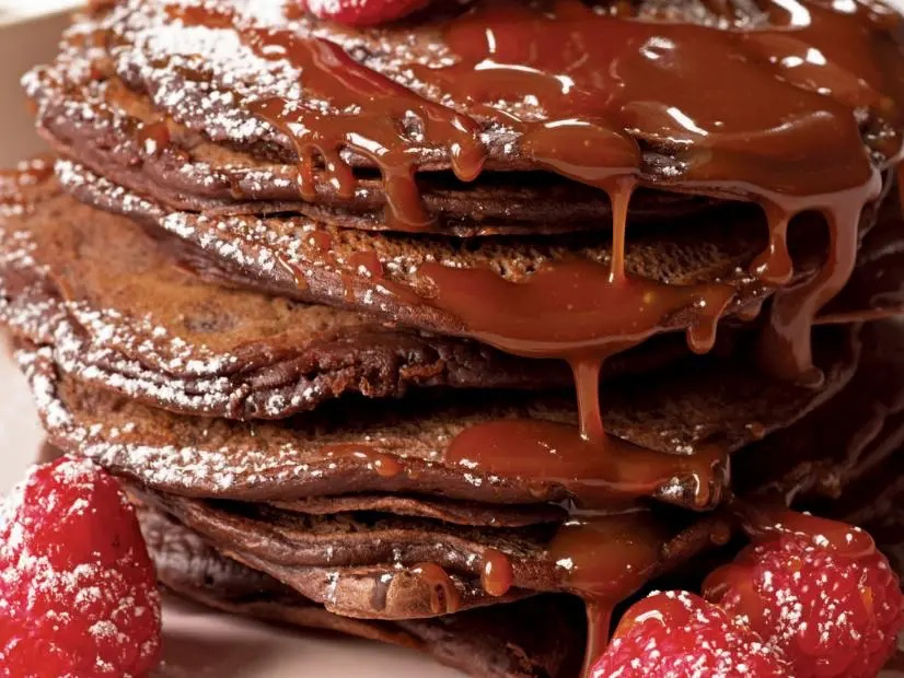 Double Chocolate Pancakes with Salted Caramel Sauce stacked with raspberries sprinkled in the side