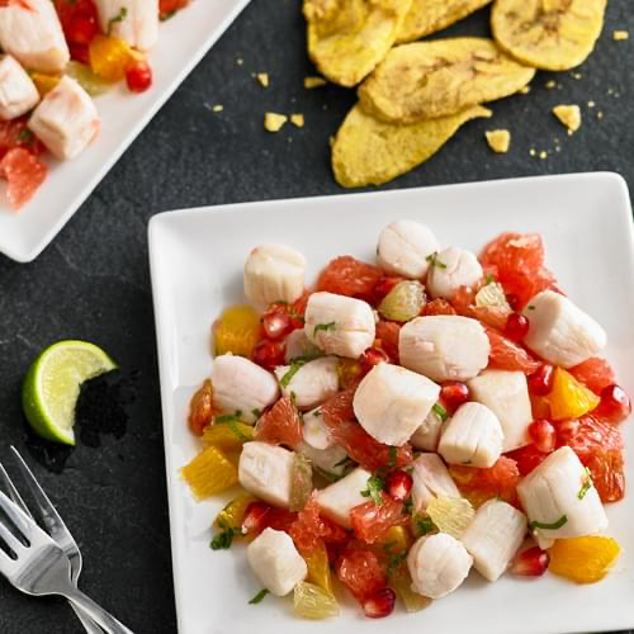 Key West Citrus Scallop Ceviche served on white square plates with lime and plaintain chips in background