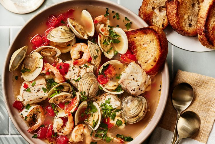 San Francisco Bay Cioppino with Scallops served in large bowl with toasted sourdough bread in background