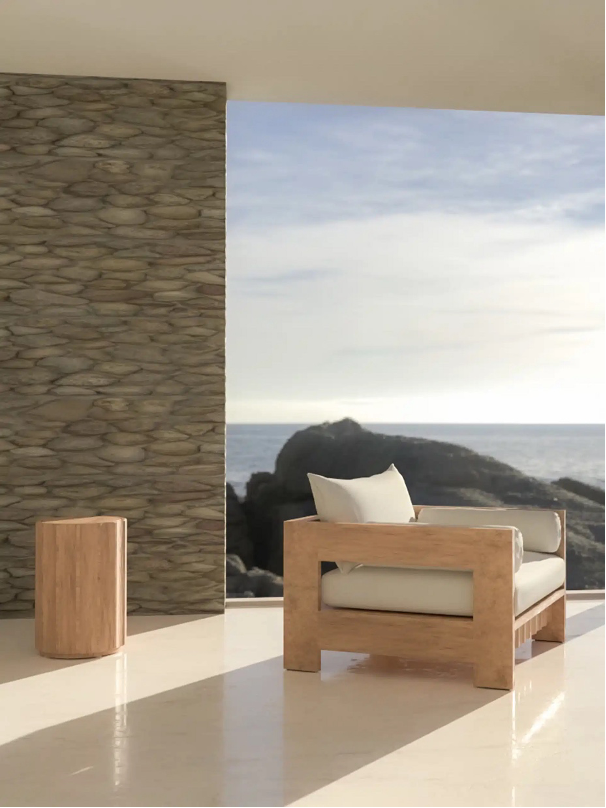 Summit Furniture's Paley Collection chair and side table on a patio with ocean and rocks in the backdrop