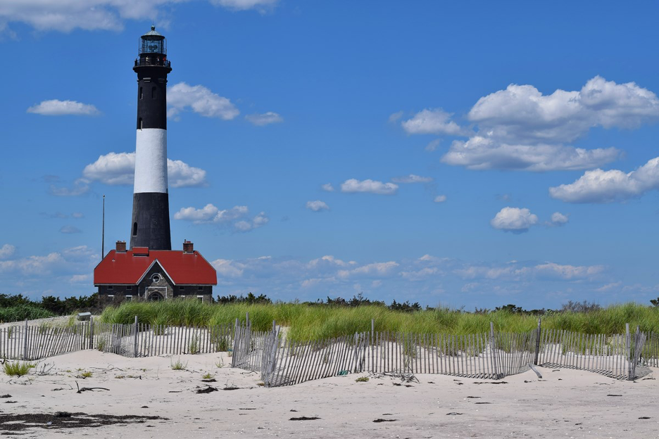 The coastline beach of Fire Island, a remote barrier island off the coast of Long Island, New York, with lighthouse in background